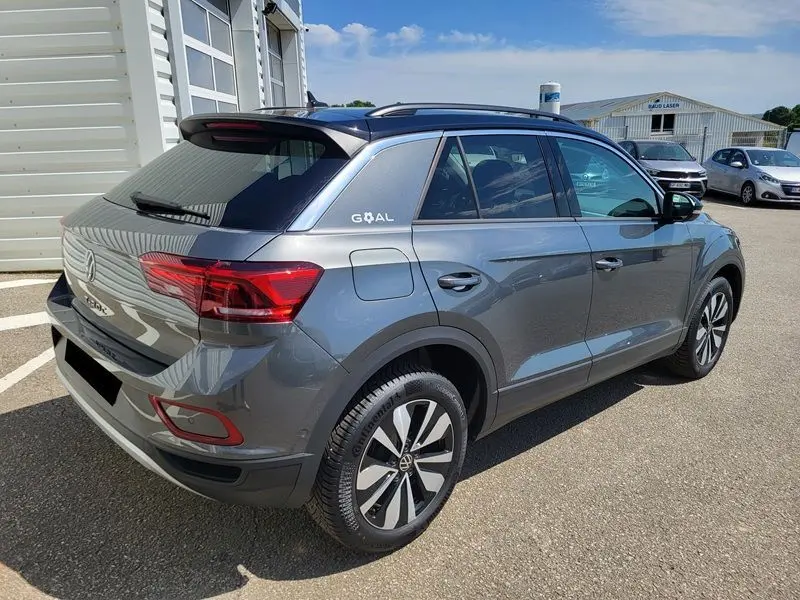 Volkswagen T-Roc gris Indium vu en 3/4 arrière droit, avec jantes alliage et attelage amovible visible.