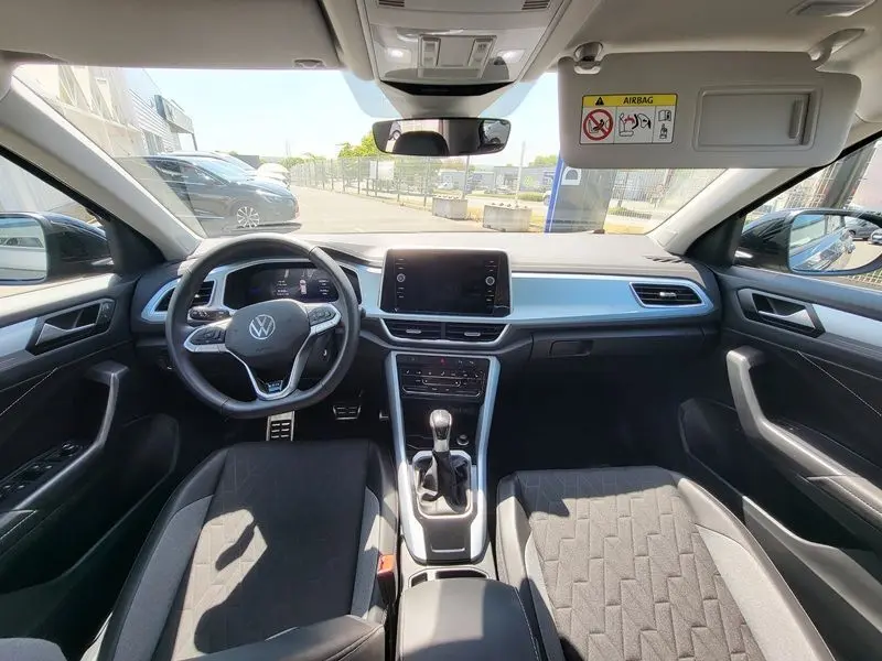 Vue intérieure avant du Volkswagen T-Roc 2025, tableau de bord moderne avec écran tactile et volant multifonction.