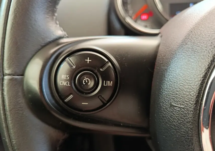 Gros plan sur la commande de régulateur de vitesse au volant cuir noir d'une MINI Countryman 2019.