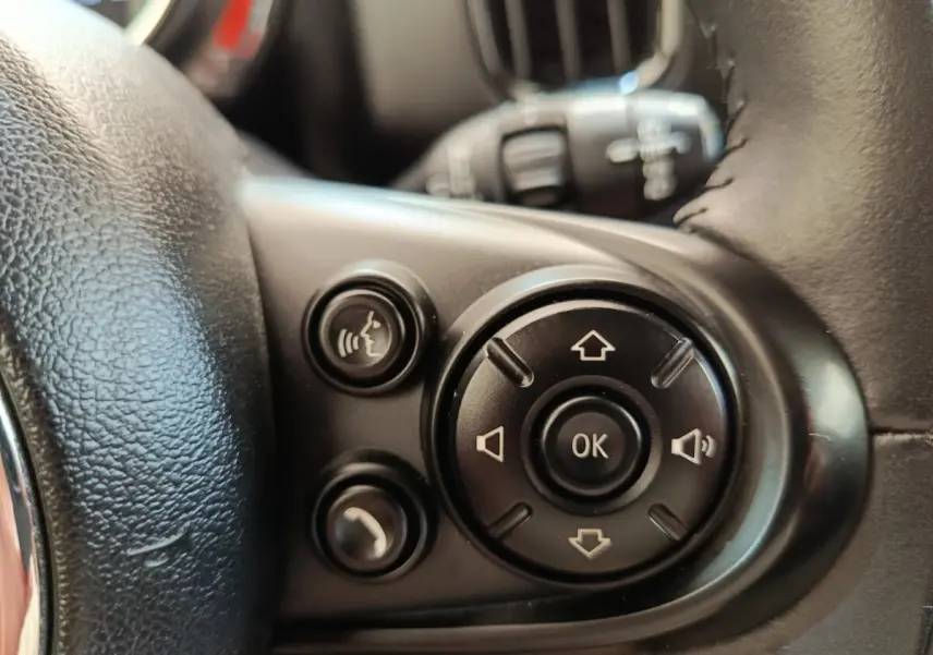 Gros plan sur les commandes multifonctions noires du volant cuir d'une MINI Countryman noir, côté gauche.