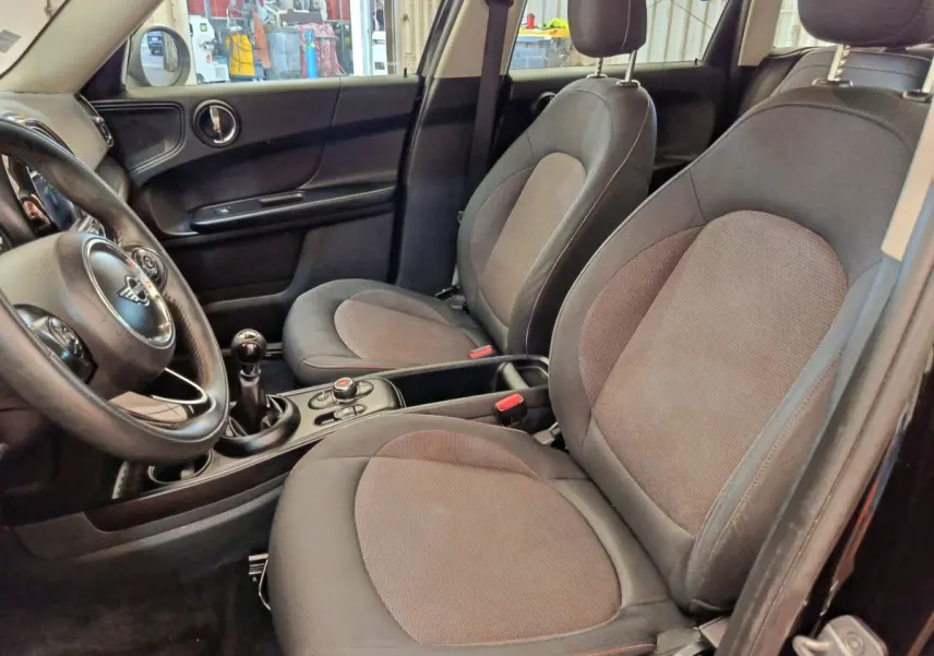 Vue intérieure côté conducteur du MINI Countryman noir 2019, montrant les sièges avant et le volant cuir multi-fonctions.
