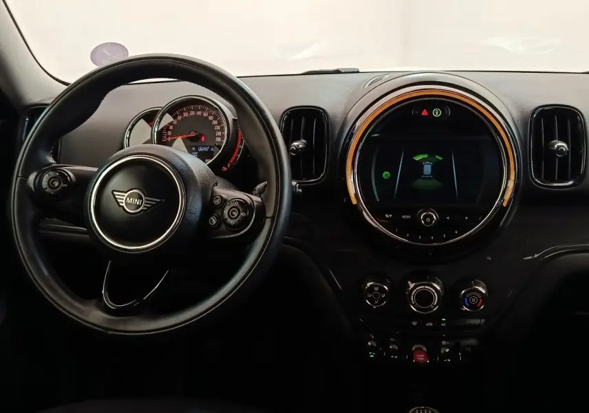 Vue intérieure centrée sur le volant cuir et le tableau de bord numérique circulaire d'une MINI Countryman noire de 2019.