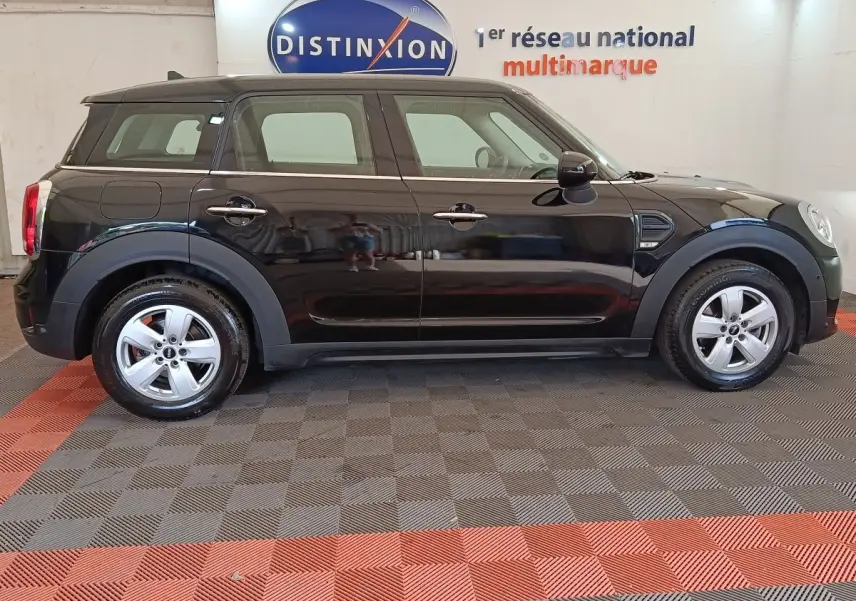 Vue latérale droite d'une MINI Countryman noire de 2019, avec jantes argentées et toit noir dans un showroom.