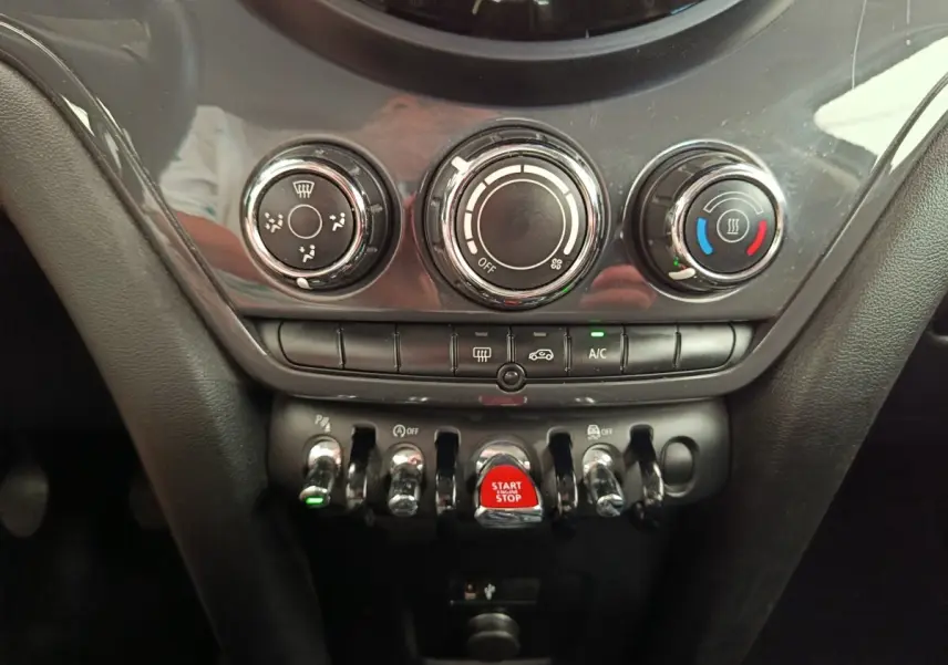 Vue rapprochée de la console centrale noire du MINI Countryman 2019 avec commandes de climatisation et bouton start/stop rouge.