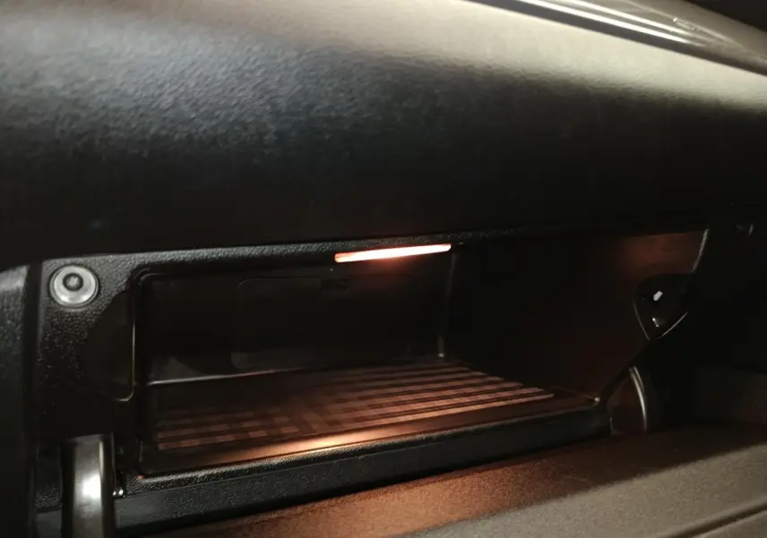 Gros plan sur la boîte à gants ouverte avec éclairage intérieur dans le tableau de bord noir du MINI Countryman 2019.