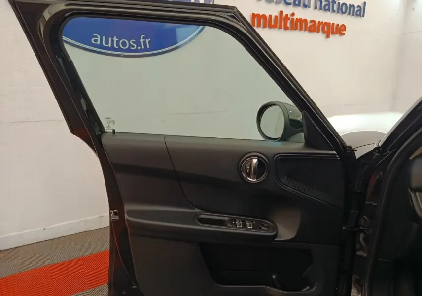 Vue rapprochée de la porte avant gauche noire ouverte d’une MINI Countryman 2019, montrant les commandes de vitres et le rétroviseur.