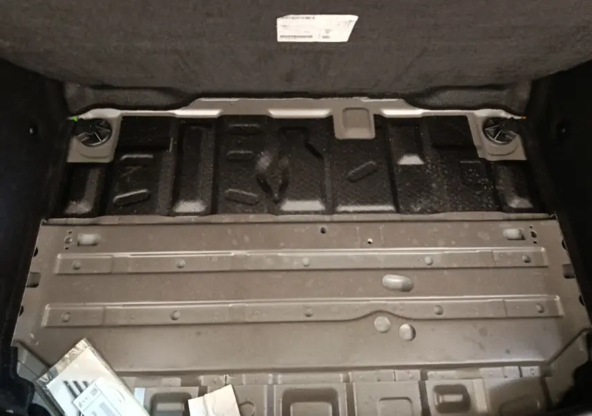 Vue rapprochée de la structure métallique du coffre arrière d’une MINI Countryman noire, sans la moquette.