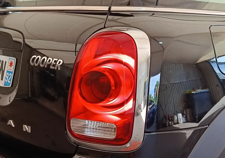 Gros plan sur le feu arrière droit rouge et l’inscription Cooper du coffre d’un MINI Countryman noir.