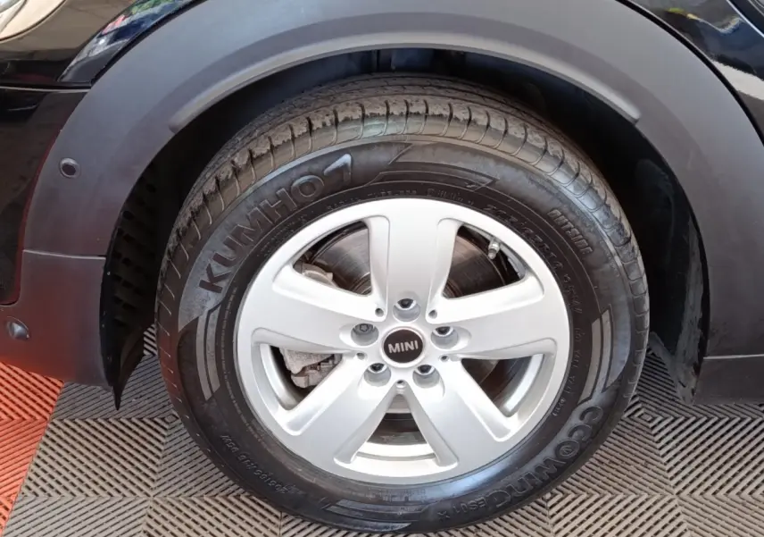 Gros plan sur la roue avant gauche d’une MINI Countryman noire, jante argentée à 5 branches et pneu Kumho.