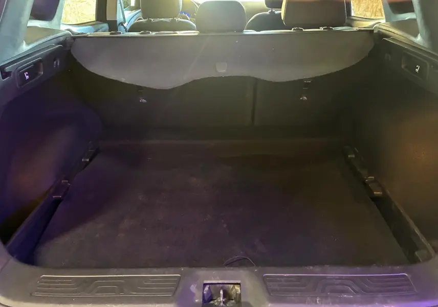 Vue intérieure du coffre spacieux et noir du Renault Kadjar gris, avec banquette arrière visible en arrière-plan.
