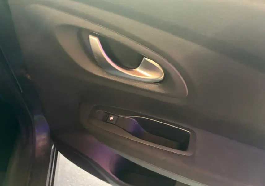 Poignée intérieure et commande de lève-vitre côté gauche du Renault Kadjar gris, finition tissu noir.