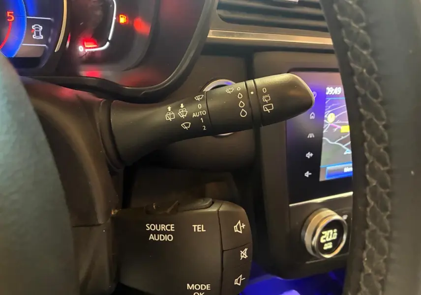 Vue rapprochée du volant côté gauche du Renault Kadjar gris 2019, montrant commandes audio et essuie-glace, avec écran GPS en arrière-plan.