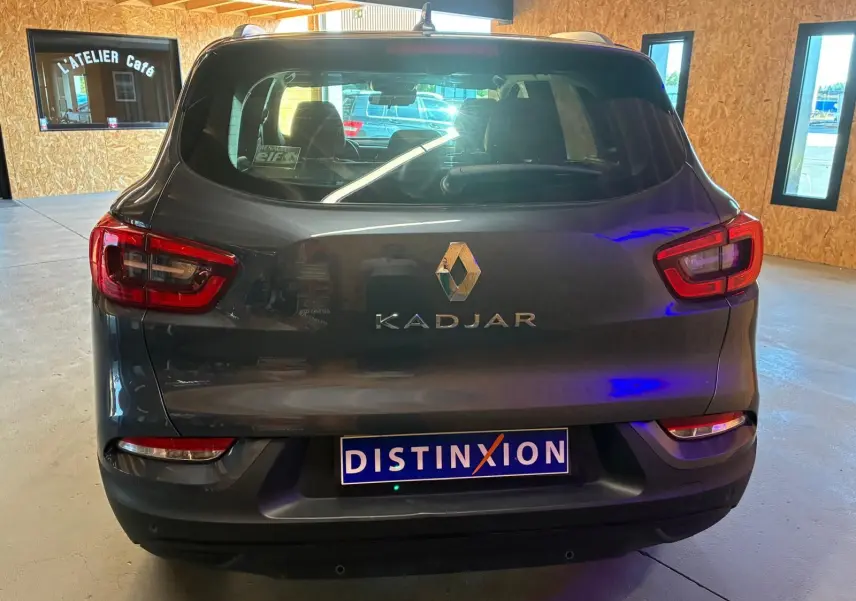 Vue arrière d’un Renault Kadjar gris 2019 avec feux arrière allumés et plaque DISTINXION visible en intérieur.