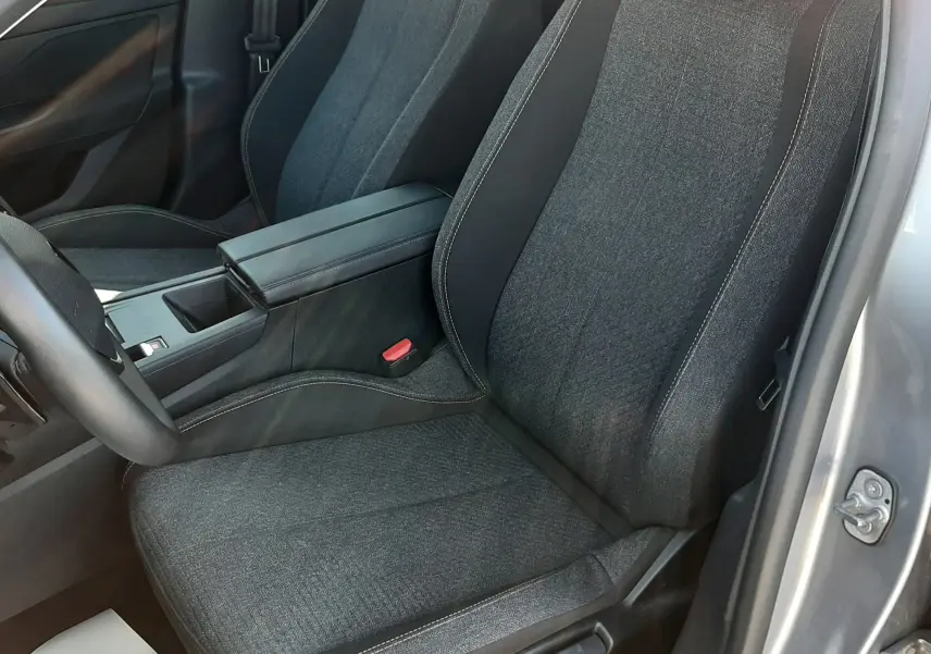 Vue intérieure côté conducteur de la Peugeot 308 III Hybrid 145ch Style 2025, siège tissu gris avec surpiqûres contrastées.