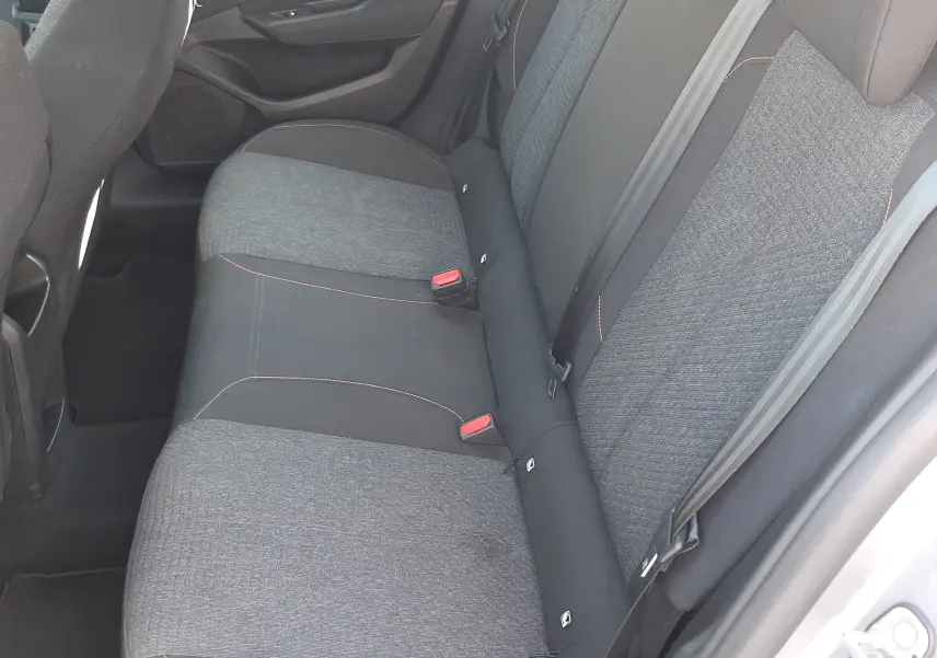 Vue intérieure côté droit des sièges arrière en tissu gris et noir avec surpiqûres rouges d'une Peugeot 308 III Hybrid 2025.
