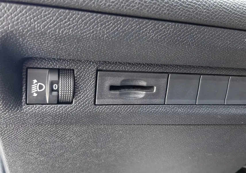 Détail intérieur montrant le réglage de hauteur des phares sur la planche de bord noire du Peugeot 308 gris Artense.