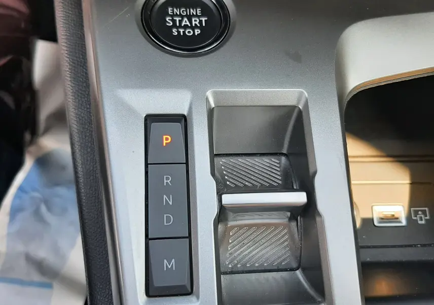 Gros plan sur la console centrale de la Peugeot 308 III Hybrid 2025, avec bouton start/stop et sélecteur de boîte auto gris.
