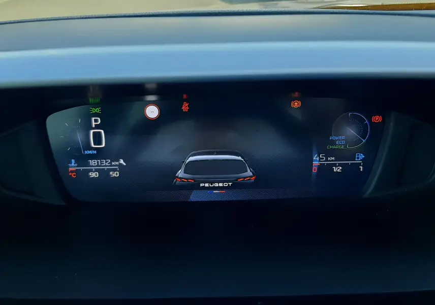 Tableau de bord numérique de la Peugeot 308 III Hybrid 145ch Style, affichant la vitesse à 0 km/h et l'autonomie hybride.