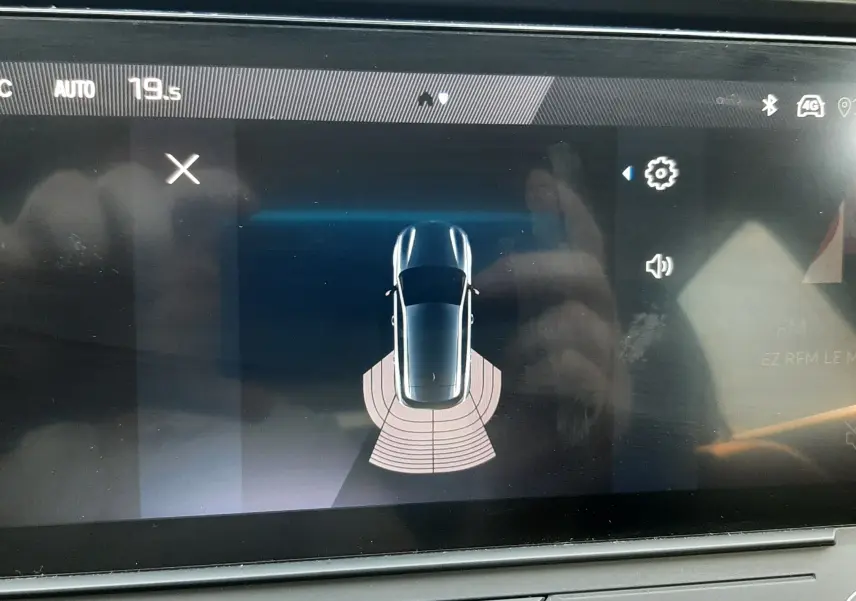 Écran tactile intérieur de la Peugeot 308 III Hybrid gris Artense montrant la vue de dessus du véhicule avec capteurs arrière actifs.