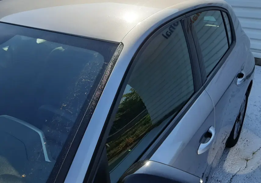 Vue 3/4 avant droit de la Peugeot 308 gris Artense 2025 avec rétroviseur noir brillant et vitrage teinté.