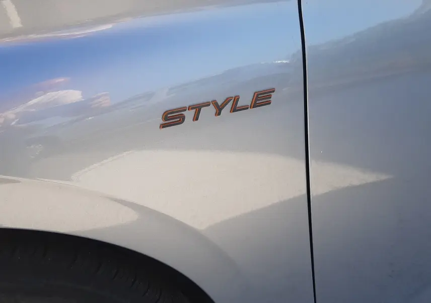 Détail de l'aile avant droite gris Artense de la Peugeot 308 III Hybrid avec l’inscription STYLE en relief.