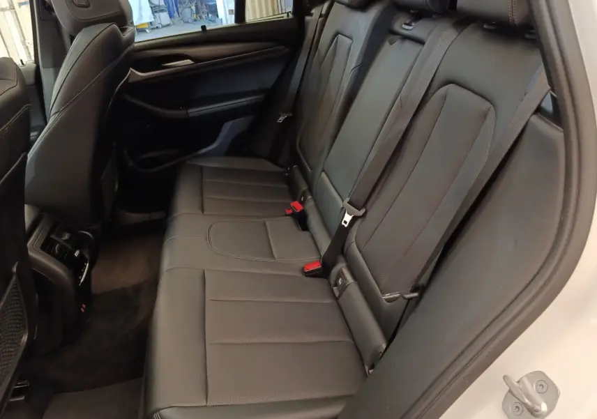 Vue intérieure côté droit des sièges arrière en cuir noir du BMW X3 blanc xDrive30e 2023, avec ceinture de sécurité visible.