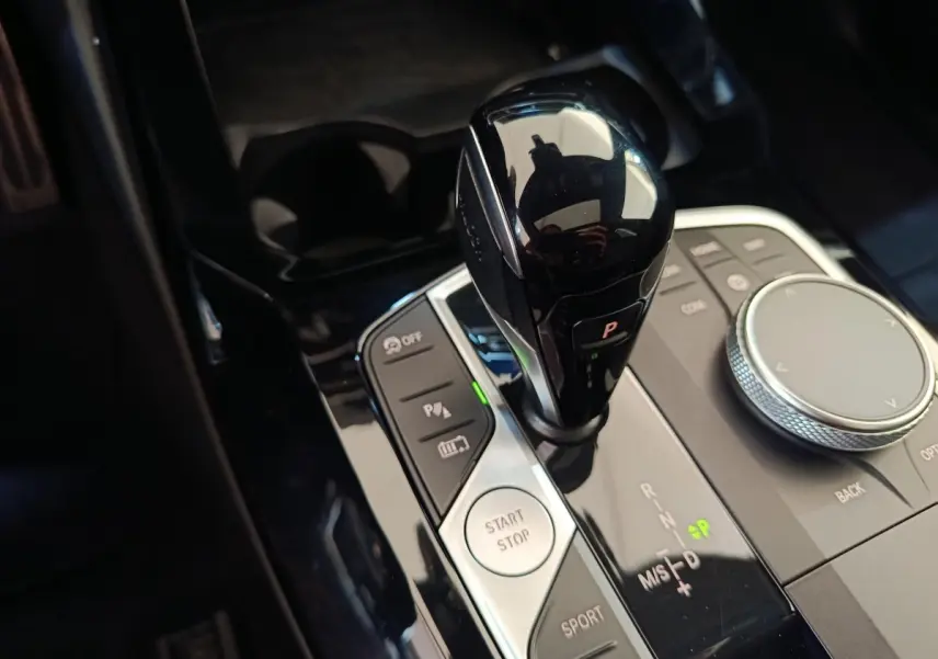 Gros plan sur la commande de boîte automatique noire et les boutons de contrôle du BMW X3 xDrive30e blanc.