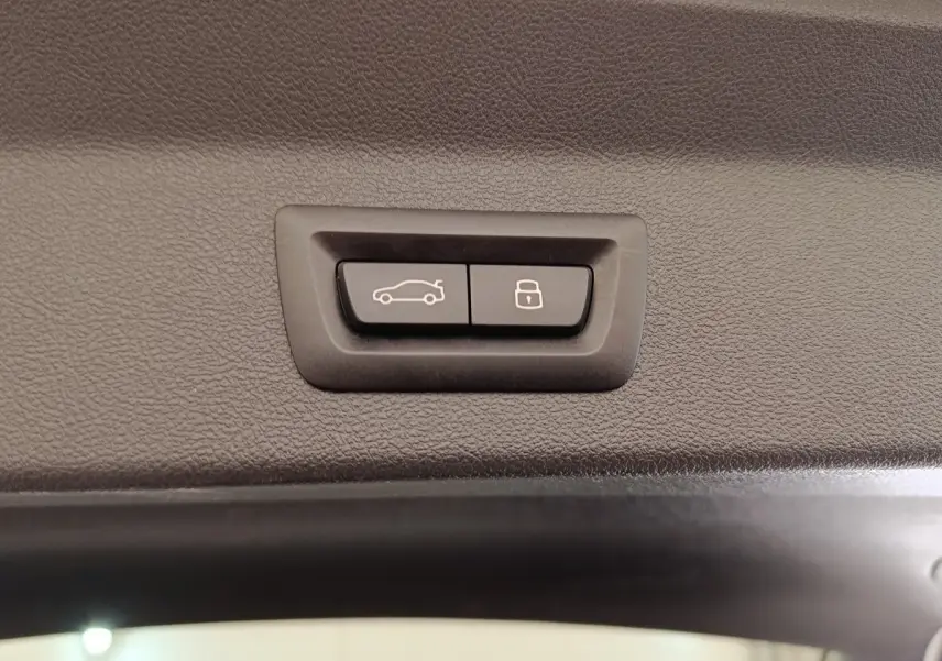 Boutons d'ouverture et de verrouillage du coffre sur la garniture intérieure d'un BMW X3 blanc hybride rechargeable.
