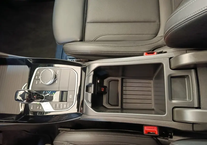 Vue plongeante sur la console centrale noire et les sièges en cuir gris foncé du BMW X3 xDrive30e 2023.