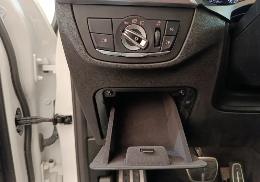 Détail intérieur côté gauche de la BMW X3 xDrive30e 2023, avec commande des phares et rangement ouvert.
