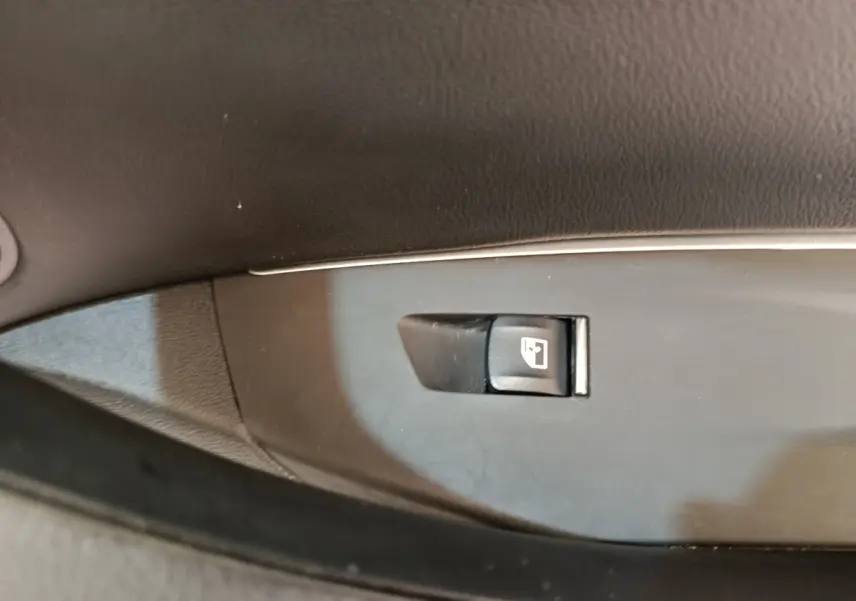 Gros plan sur le bouton de verrouillage des portes sur la garniture intérieure noire d'une BMW X3 blanche hybride rechargeable.
