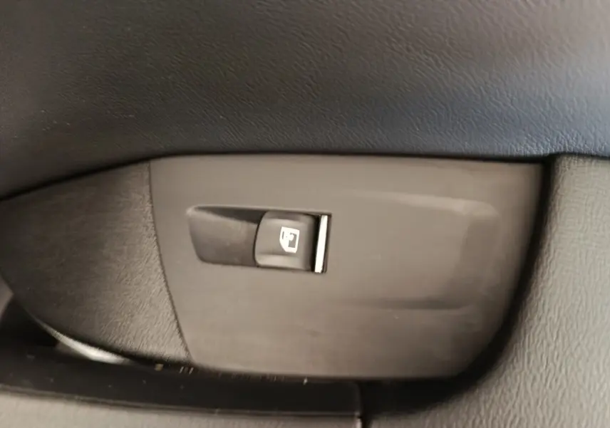 Gros plan sur le bouton d'ouverture de trappe à carburant dans l'habitacle du BMW X3 blanc xDrive30e 2023.