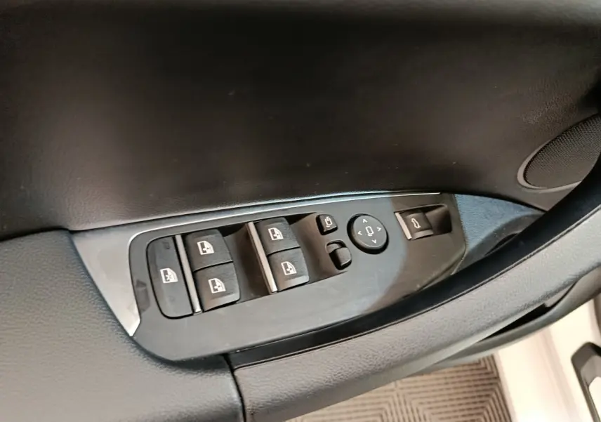 Détail des commandes de lève-vitres et rétroviseurs sur la porte côté conducteur d’un BMW X3 blanc 2023.