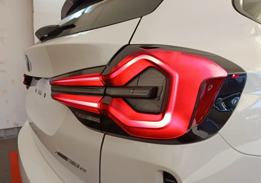 Gros plan sur le feu arrière droit rouge et noir d’un BMW X3 blanc xDrive30e 2023, vue arrière côté droit.