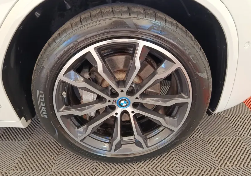 Gros plan sur la roue avant gauche blanche BMW X3 xDrive30e avec jante alliage noire et logo BMW central.