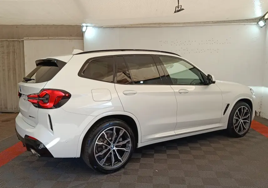 BMW X3 xDrive30e blanc en vue 3/4 arrière droit, avec jantes alliage et feux arrière LED distinctifs.