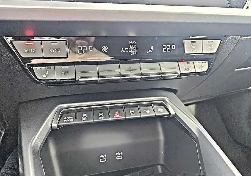 Détail du tableau de bord noir de l'Audi A3 Sportback 2026 avec commandes climatisation et boutons multifonctions.