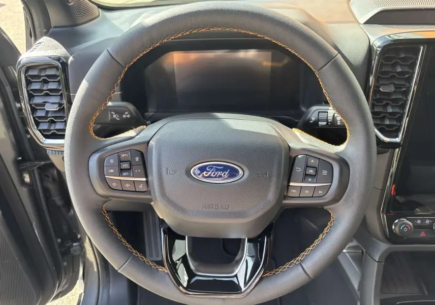 Vue rapprochée du volant en cuir noir avec surpiqûres marron du Ford Ranger gris carbone 2026, tableau de bord partiel visible.