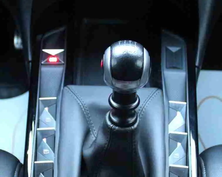 Vue rapprochée du levier de vitesse manuel en cuir noir du DS3 Crossback, entouré de boutons de commande brillants.