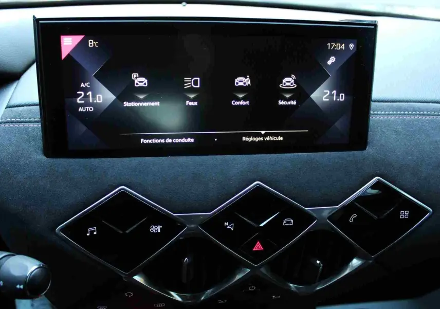 Gros plan sur l’écran tactile et les commandes en losange du tableau de bord du DS3 Crossback, finition noire élégante.