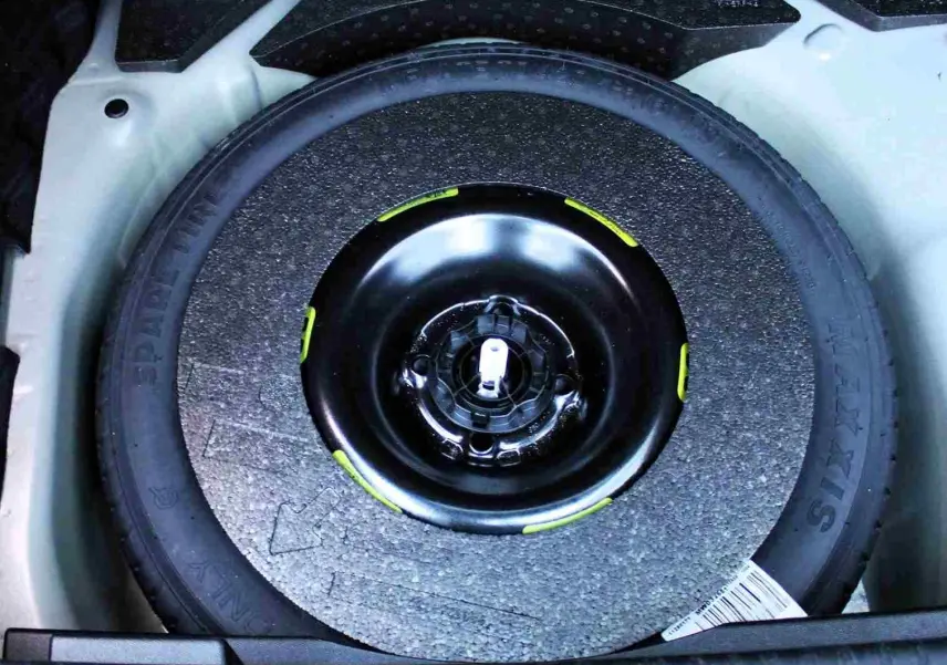 Gros plan sur la roue de secours noire logée dans le coffre, entourée d'un espace gris clair du DS3 Crossback.