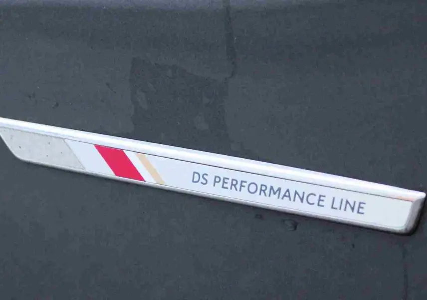 Gros plan sur l’insigne latéral "DS Performance Line" sur la carrosserie gris platinium métallisé du DS3 Crossback.