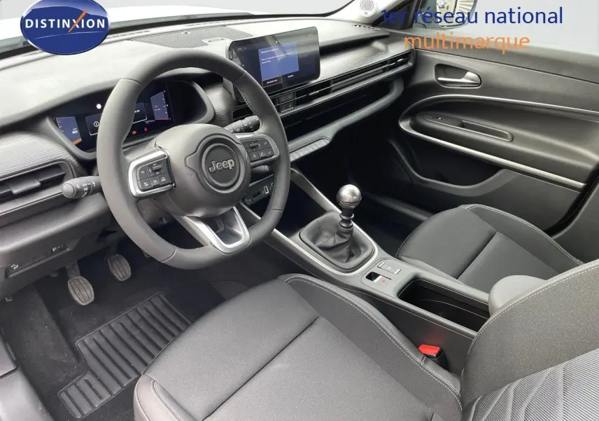 Intérieur noir du Jeep Avenger 2024, vue côté conducteur montrant volant, tableau de bord digital et levier de vitesse manuel.