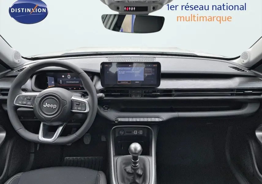 Intérieur du Jeep Avenger 2024 vue de face, tableau de bord noir avec écran tactile et levier de vitesse manuel.