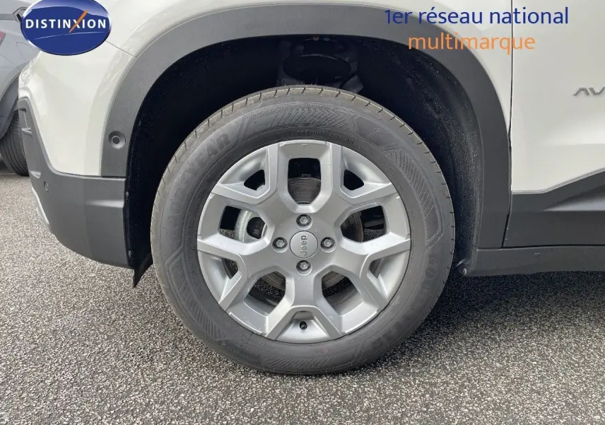 Gros plan sur la roue avant gauche d’un Jeep Avenger blanc neige avec jante alliage et pneus Goodyear.