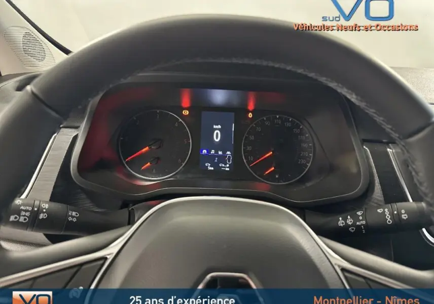 Vue intérieure du tableau de bord du Renault Trafic Fourgon gris 2025, avec volant et compteurs numériques allumés.