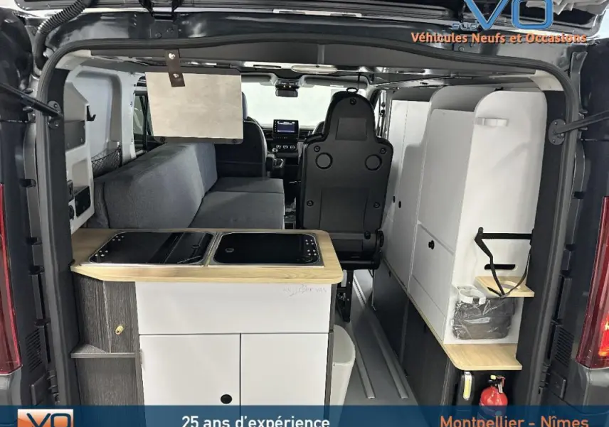 Vue arrière intérieure du Renault Trafic Fourgon gris 2025 aménagé avec kitchenette et banquette côté gauche.