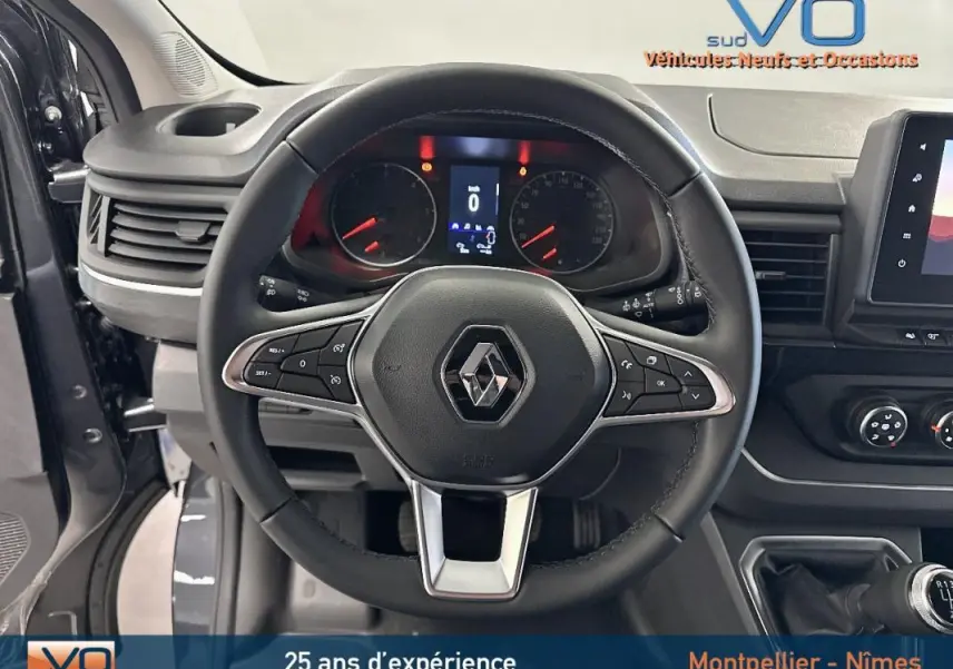 Vue intérieure centrée sur le volant noir du Renault Trafic Fourgon gris 2025 avec tableau de bord et commandes visibles.