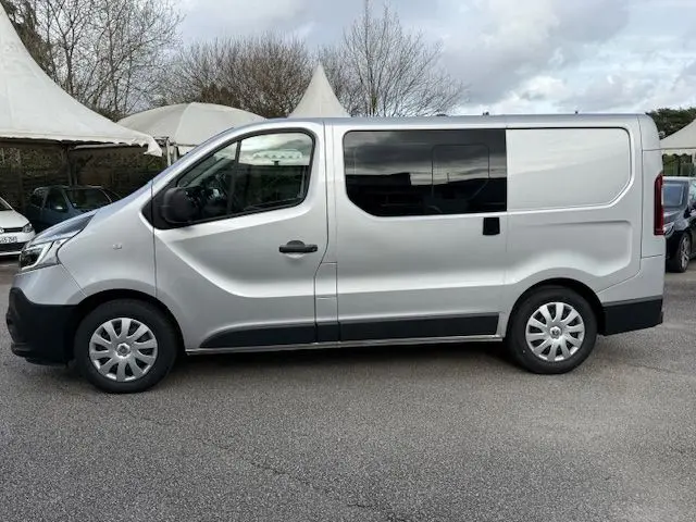 Vue latérale gauche du Renault Trafic Fourgon gris platine avec porte coulissante et vitres teintées.