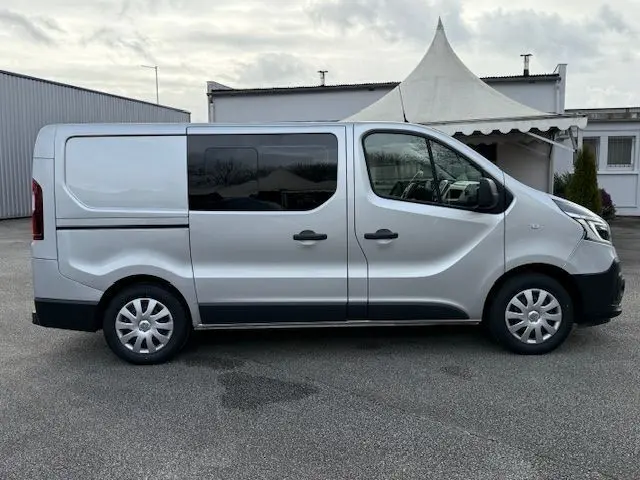 Profil droit d’un Renault Trafic Fourgon gris platine avec porte latérale coulissante et vitres teintées.